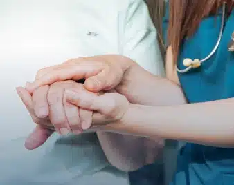 Nurse holding an older patient's hands