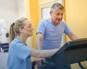 Therapist assisting a man using exercise equipment during cardiac rehab
