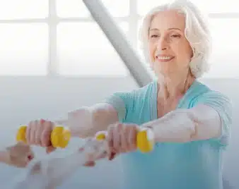 Older adult lifting light hand weights during cardiopulmonary rehab