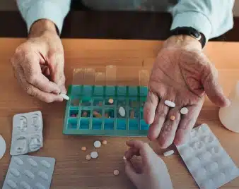 Person sorting daily medications into a weekly pill organizer