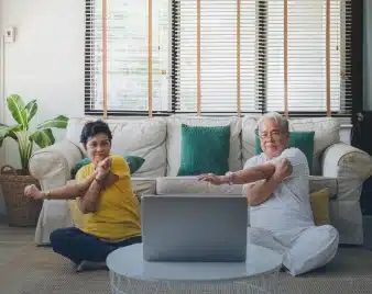Two people exercising at home while following a program on a laptop