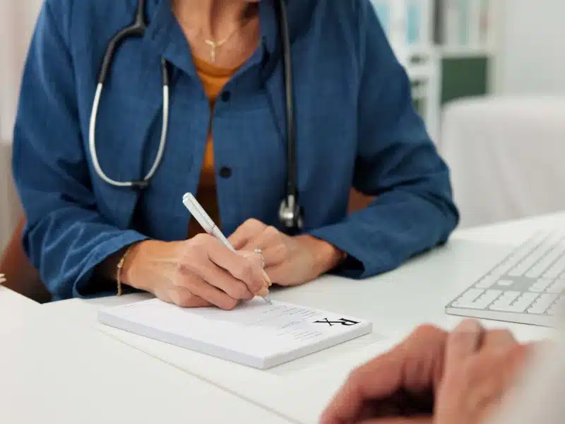 Girard Medical Center provider writing a patient referral at a clinic desk