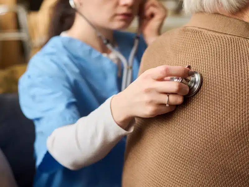 Respiratory therapist listening to an older patient's lungs with a stethoscope